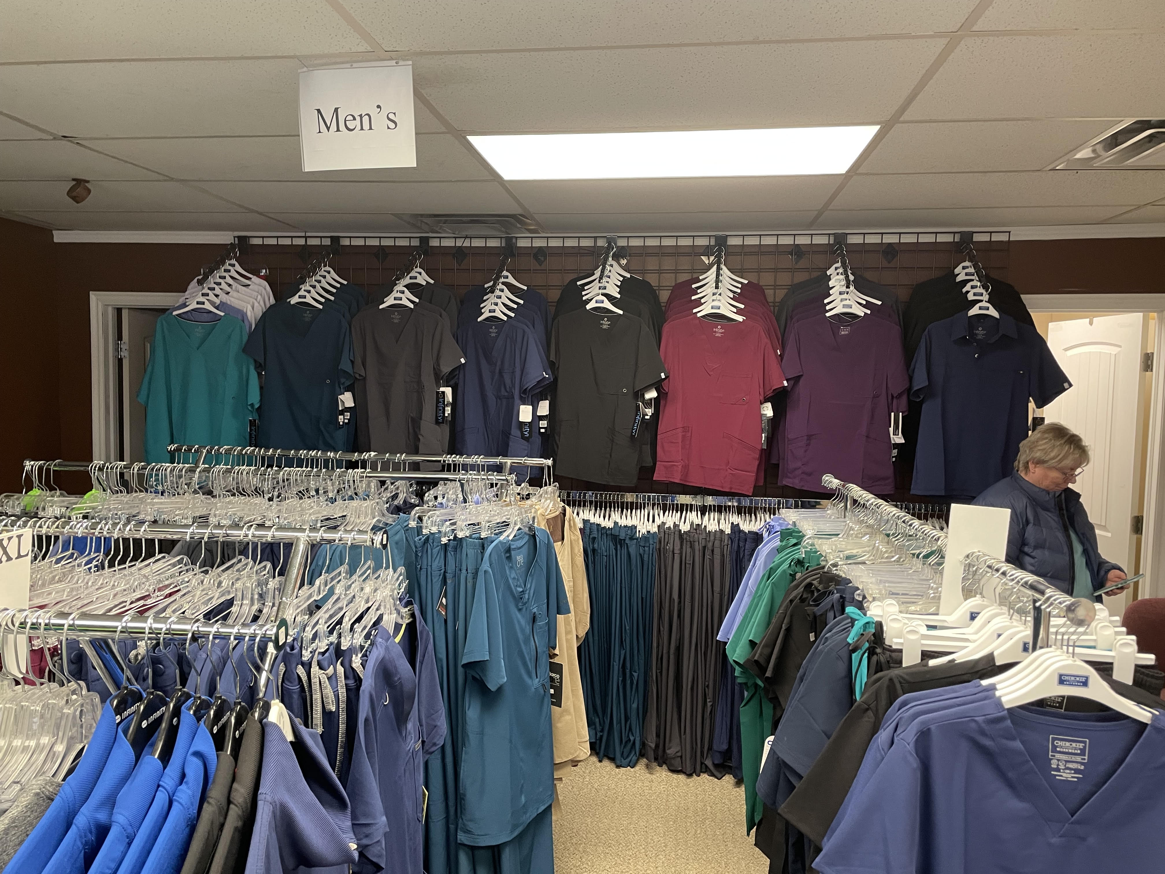 Men's scrub top section with a range of colors displayed on the wall at Scrub JCT